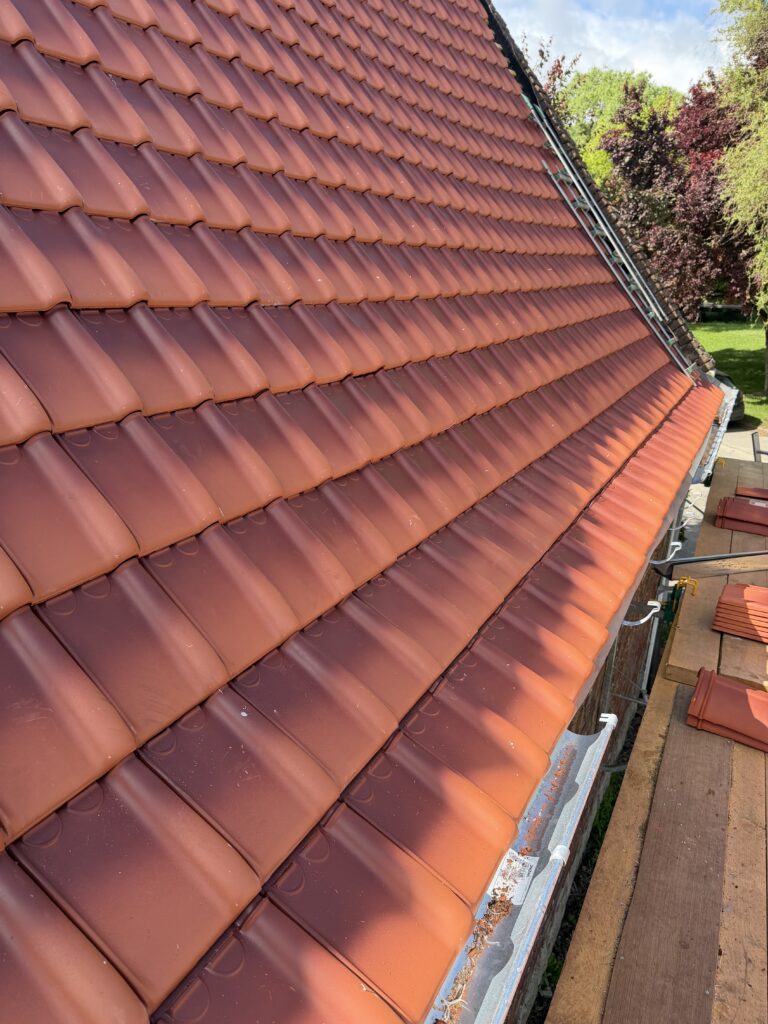Toit en tuiles orange en terre cuite sur une maison avec charpente traditionnelle